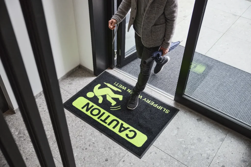 Ohutusmatt sissepääsu ees neoonkollase tekstiga