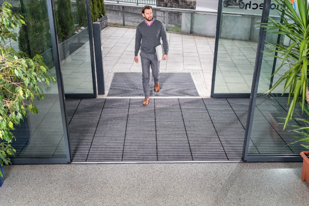 Alumiiniumprofiiliga harjasmatid ja poritõkkesüsteem ärihoone sissepääsus