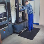 Floorstudio must ergonoomiline kummimatt töölise jalge all tootmishoones seadme taga