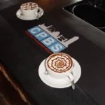 Logoga reklaammatt kohvikuletil koos kohvitassidega