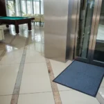 Tumesinine siseruumi porimatt liftide ja piljardilaua vahel heledal plaatpõrandal