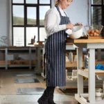 Ergonoomilised matid 49 Naiskokk töötamas köögis saare tüüpi laua taga, seistes FloorStudio mustal ergonoomilisel matil