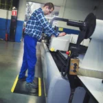 Ergonoomilised matid 56 Kollaste ohutusservadega must FloorStudio ergonoomiline matt tööstusliku masina taga töötava mehe jalgade all