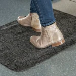 Pruun vaiba tekstuuriga ergonoomiline matt saabastega seisja jalgade all