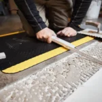 Ergonoomilised matid 69 Must ristkülikukujuline FloorStudio ergonoomiline matt (85x150 cm) betoonpõrandal töömehe käte all