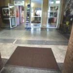 Pruun väliporimatt ühiskondliku hoone sissepääsu tuulekojas, mis kaitseb põrandaid liiva ja pori eest