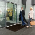 Professionaalne väliporimatt ärihoone klaasukse ees kaitsmas sissepääsu mustuse eest